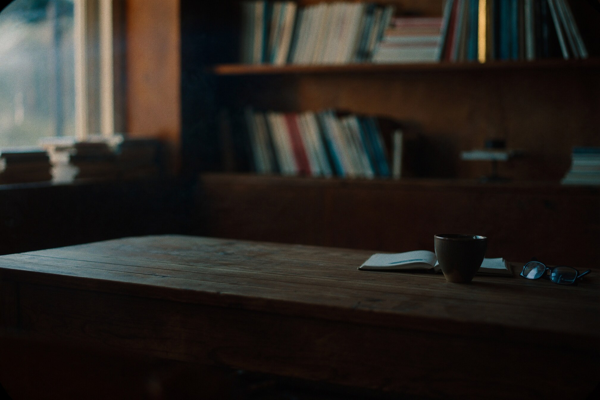 A quiet cafe-library table with books, a cup, and soft morning light.