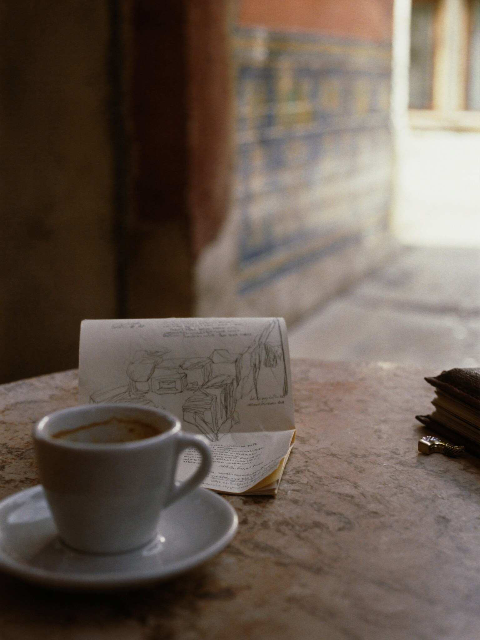An espresso cup, folded map, notebook, and tiled cafe wall in warm Lisbon morning light.