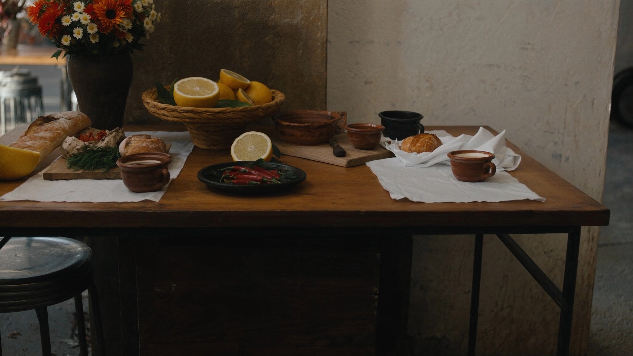 A rustic market table with citrus, clay bowls, linen, coffee, and bread in soft morning light.